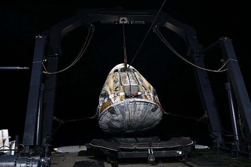 Kurtarma gemisine alınmak üzere vinç ile kaldırılan Crew Dragon aracı.